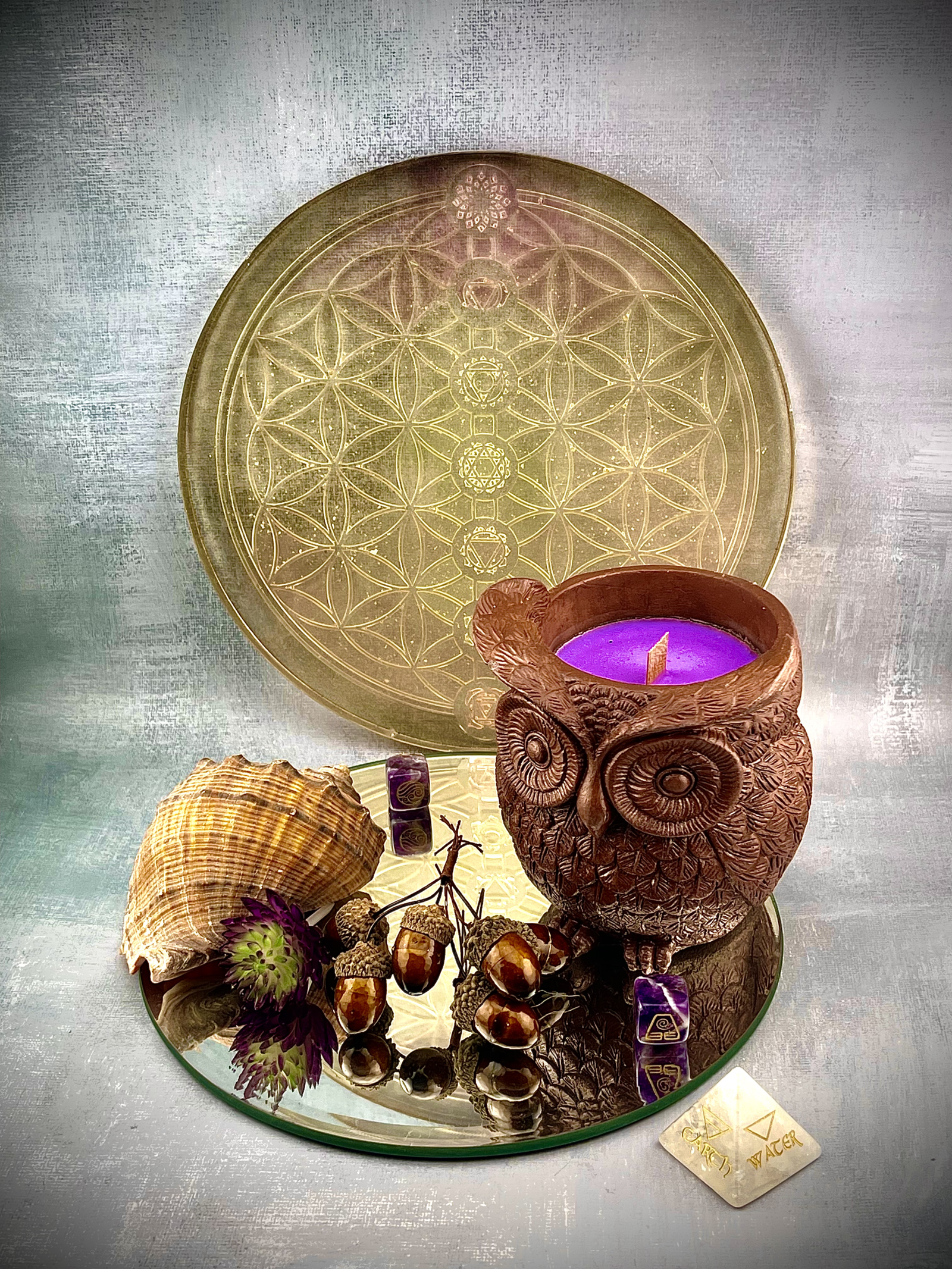 Lucentius Deutschland Eulenkerze auf Holzregal neben Spiegel mit Flower of Life und Chakra Symbolen im Hintergrund, spirituelle Meditationsdekoration