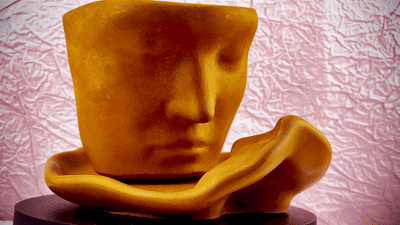 Lucentius Twin Flame candle jar shaped as male face on female tray rotating 360 degrees on turntable, showing sculptural design from all angles, beige concrete, unlit